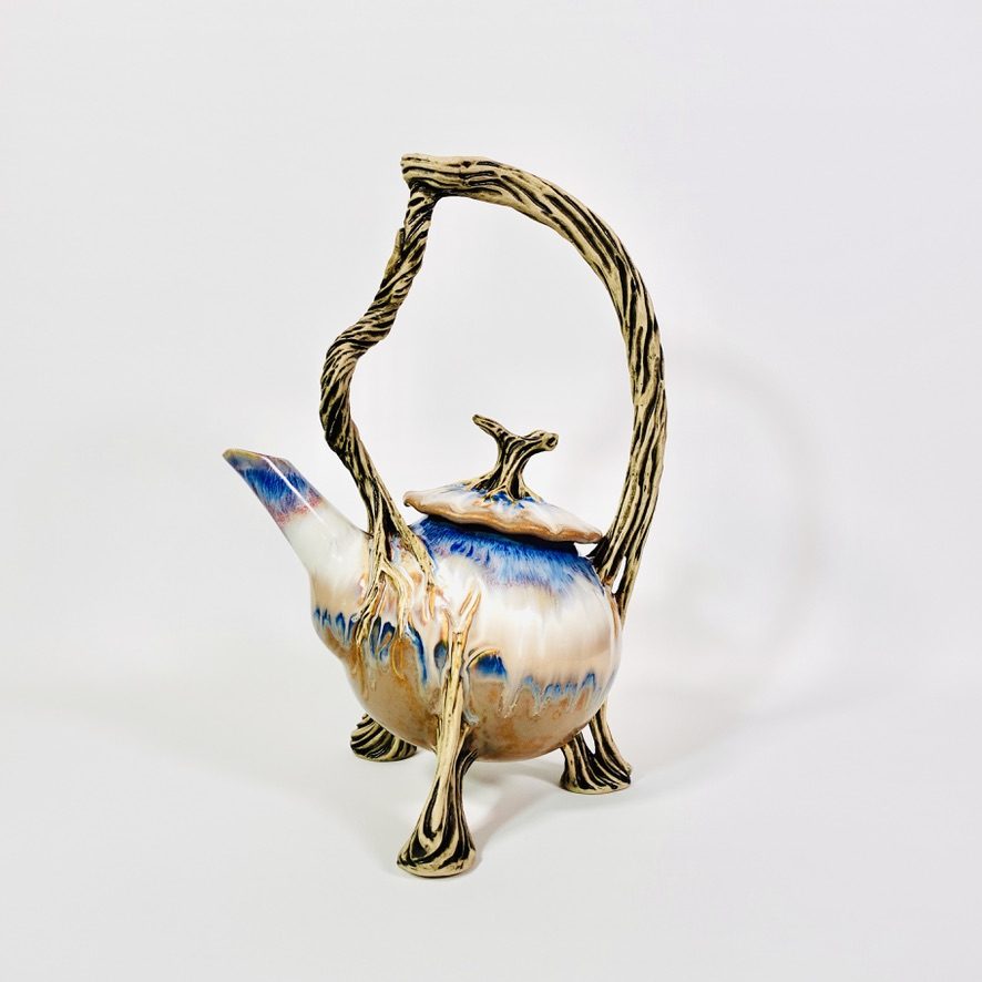 Sculptural teapot on three branch legs with an arching branch handle and blue-white glaze