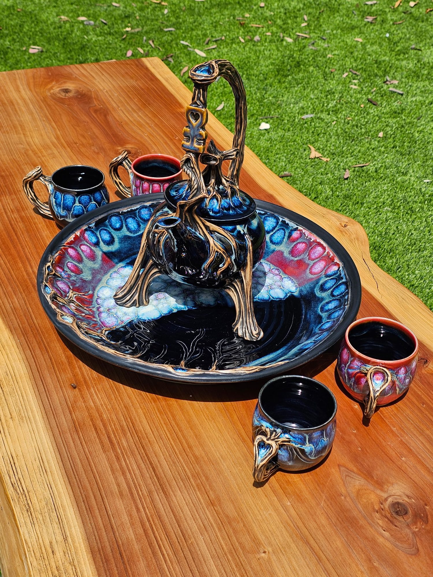 Commissioned tea set — sculpted branch handles, blue and red crystalline glaze, on a live-edge table